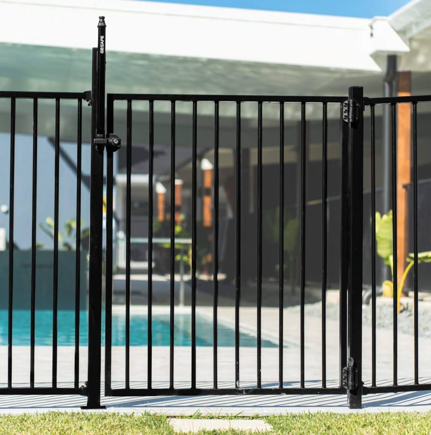 Close-up of a compliant pool gate latch and self-closing hinge